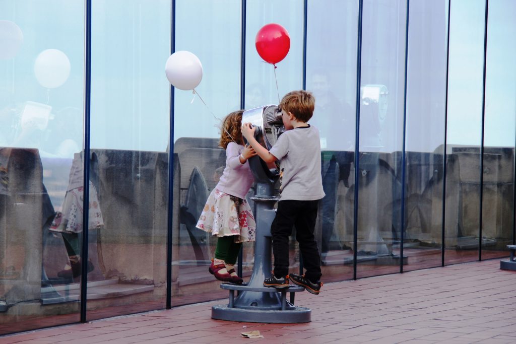 Two kids with balloons looking at eachother